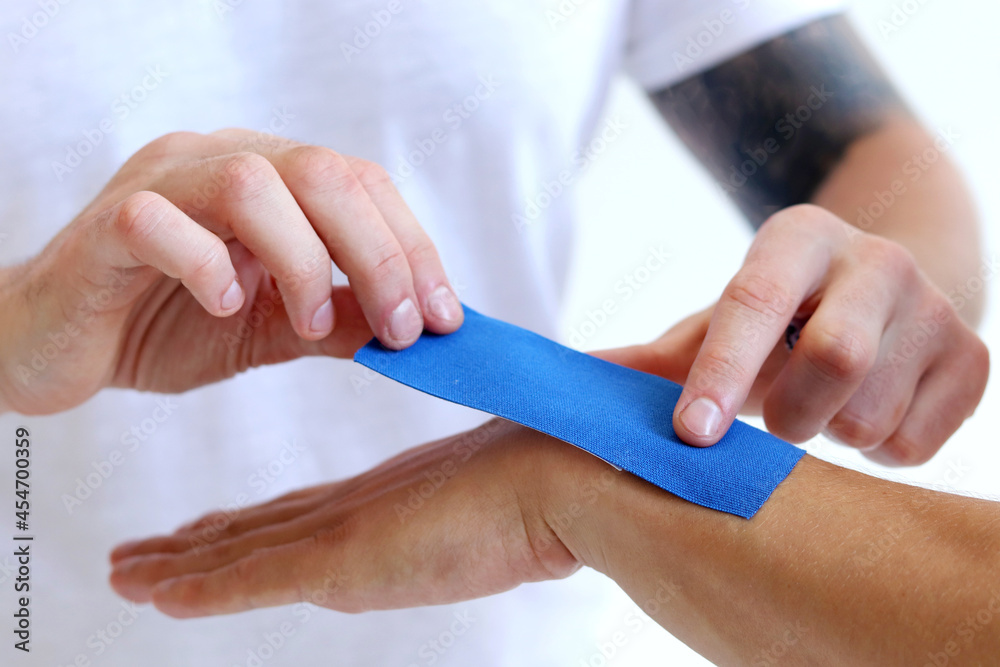 Physiotherapy treatment with therapeutic kinesiology tape for wrist pain,  aches and tension. Prevention and treatment in competitive sports. Hand  with kinesiology tape. Stock Photo | Adobe Stock