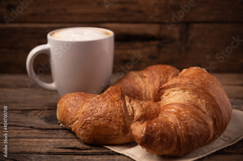 Fresh buttery croissants with coffee on rustic wooden table