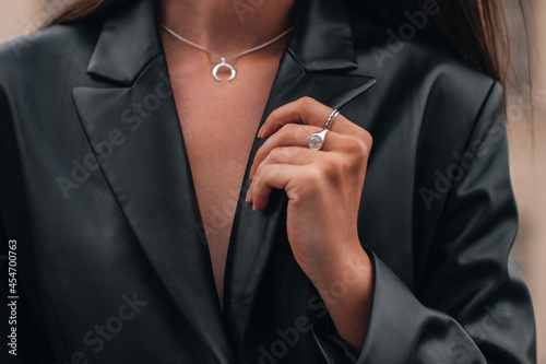 Female hands in a black stylish leather jacket and silver accessories on a female body. Jewelry and women's fashion