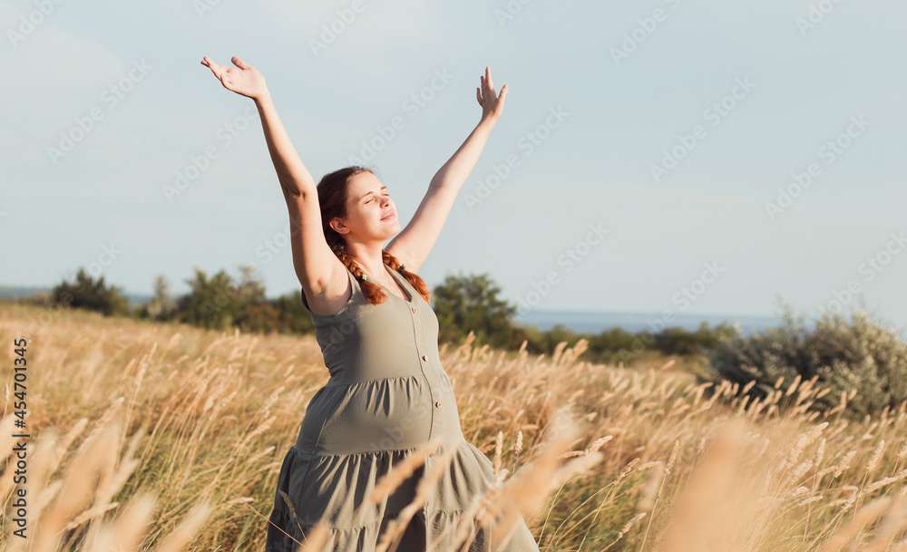 beautiful pregnant woman walks in field among dry fluffy grass enjoying sunset, relaxation on summer nature, preparation for childbirth and happy, healthy motherhood beautiful pregnant woman walks in field among dry fluffy grass enjoying sunset, relaxation on summer nature, preparation for childbirth and happy, healthy motherhood