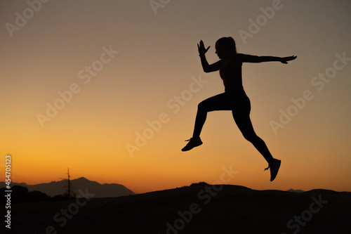 Silueta de deportista haciendo técnica de carrera en la montaña a la hora del atardecer, con espacio para texto. © Ezequiel Martínez