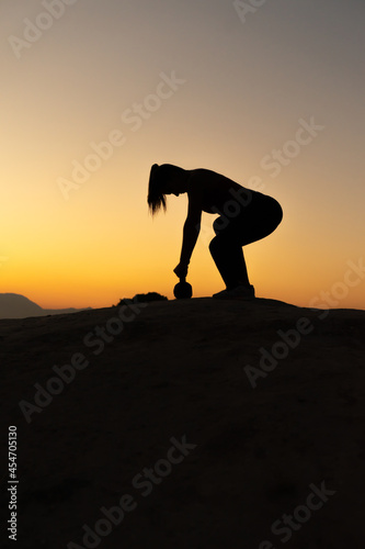 Silueta de chica entrenando con kettlebell en la hora del atardecer en la montaña. © Ezequiel Martínez