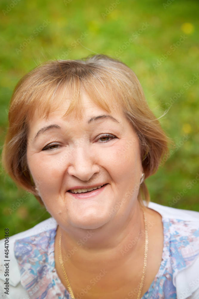 Portrait of an elderly or middle-aged woman with a green background in a park or forest in nature Portrait of an elderly or middle-aged woman with a green background in a park or forest in nature