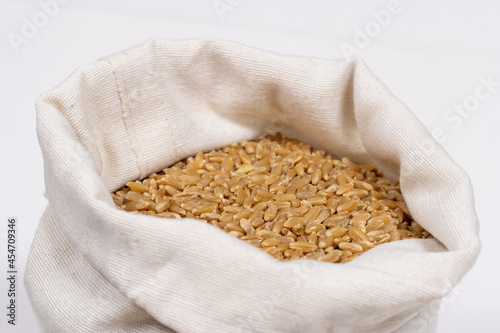Wheat grains lie in a white bag on a white background. Close-up. Soft focus