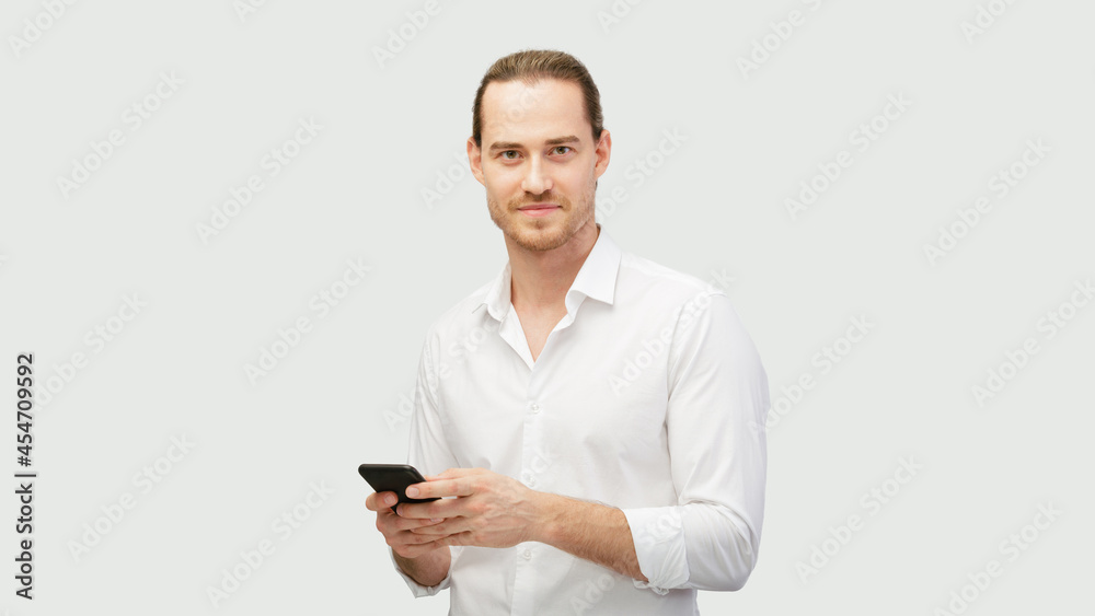 Confident and positive man with phone. Man holds smartphone in both hands and communicate via social network. Using a mobile cell in everyday life Confident and positive man with phone. Man holds smartphone in both hands and communicate via social network. Using a mobile cell in everyday life