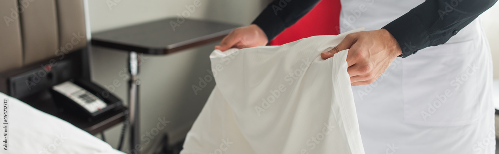 partial view of housekeeper changing bedding in hotel room, banner partial view of housekeeper changing bedding in hotel room, banner