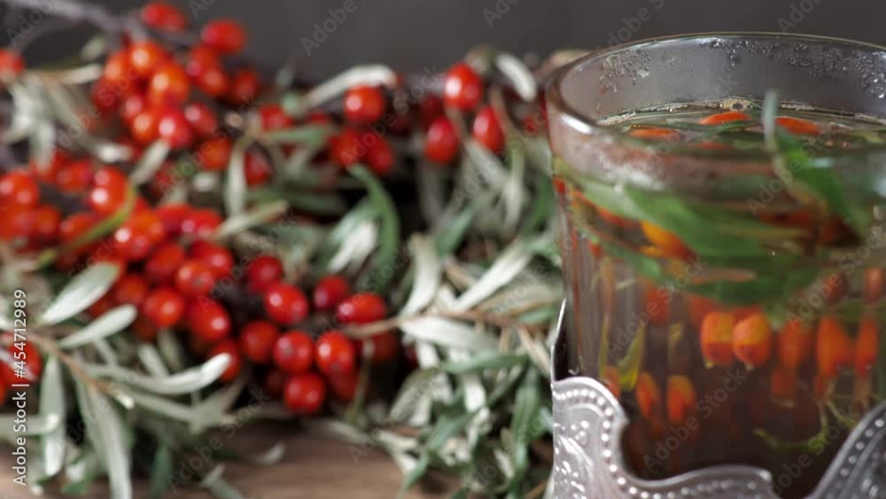 a glass of tea from Sea-buckthorn. Sea buckthorn bunches background. close up. Hippophae rhamnoides. Sea buckthorn Full ripe mellow orange berry. focus. 4k a glass of tea from Sea-buckthorn. Sea buckthorn bunches background. close up. Hippophae rhamnoides. Sea buckthorn Full ripe mellow orange berry. focus. 4k