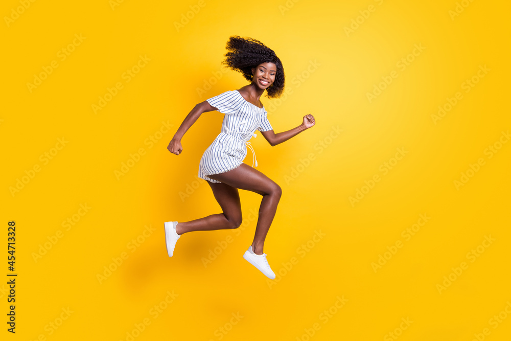Full length body size view of attractive cheerful motivated girl jumping running fast isolated over bright yellow color background Full length body size view of attractive cheerful motivated girl jumping running fast isolated over bright yellow color background