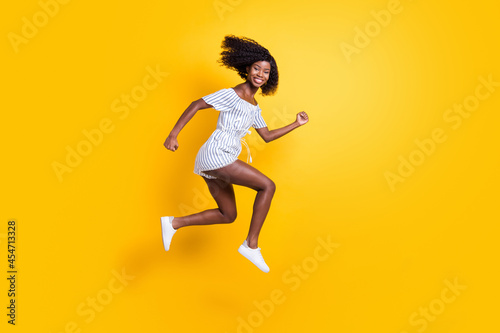 Full length body size view of attractive cheerful motivated girl jumping running fast isolated over bright yellow color background