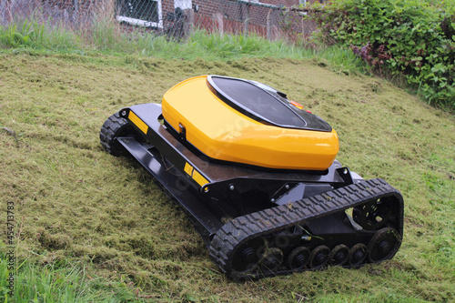 Remote controlled agricultural grass and bush cutter on a steep grassy bank