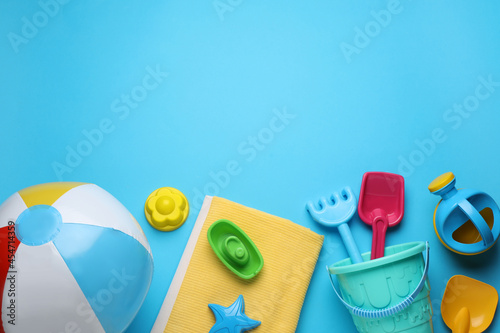 Flat lay composition with beach ball and sand toys on light blue background, space for text