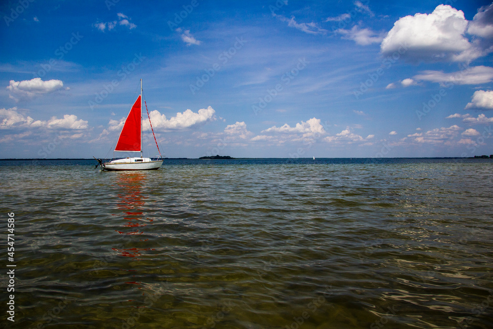 Single-masted sailboat with red sail