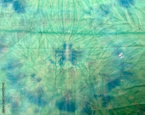 Watercolor abstract illustration. Nicely crumpled fabric. Knotted batik. Abstract painting. Spray paint on fabric. Blue stains of paint on a green background.