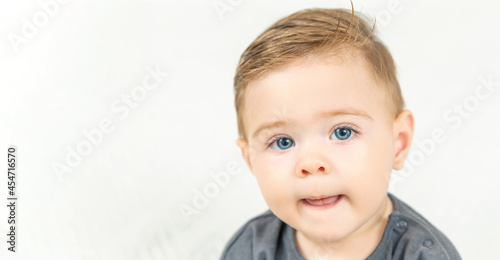 Headshot portrait of adorable smiling baby boy, shows tongue. Copy space, white background