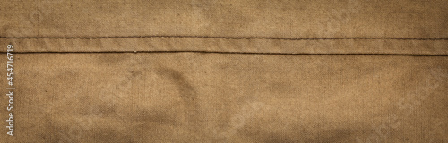 Wide panoramic surface texture of army rough khaki fabric with seam and dark vignette. Template for design and site header photo