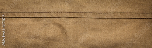 Wide panoramic surface texture of army rough khaki fabric with seam and dark vignette. Template for design and site header