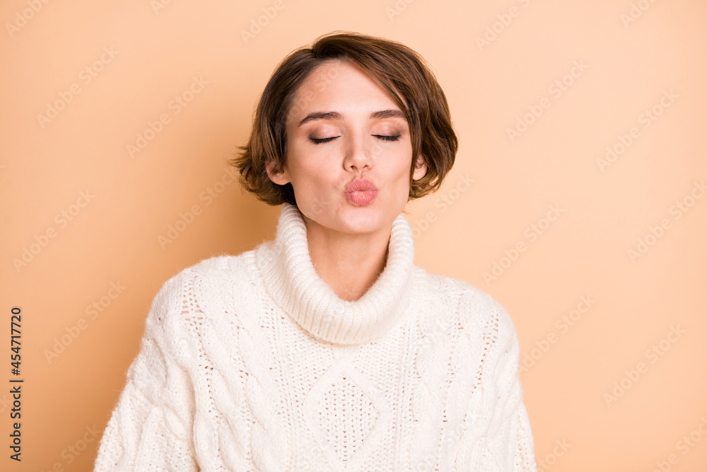 Photo portrait of beautiful girl with short hair sending air kiss on date isolated on pastel beige color background Photo portrait of beautiful girl with short hair sending air kiss on date isolated on pastel beige color background