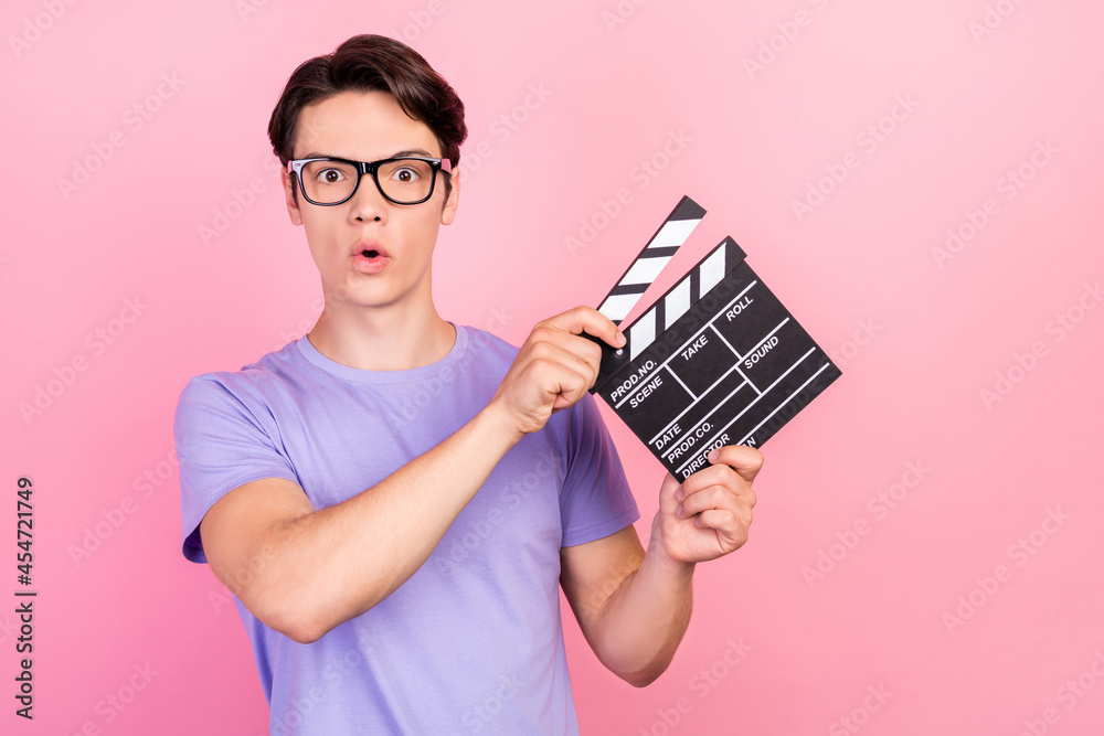 Portrait of attractive amazed guy filmmaker assistant using board producing movie isolated over pink pastel color background Portrait of attractive amazed guy filmmaker assistant using board producing movie isolated over pink pastel color background