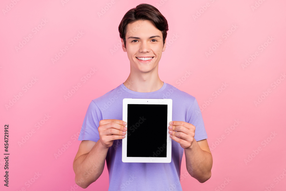 Portrait of attractive cheerful guy holding in hands device copy space display isolated over pink pastel color background