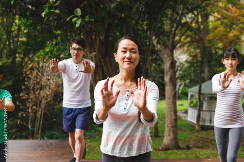 Happy asian parents, son and daughter exercising outdoors, practicing tai chi photo