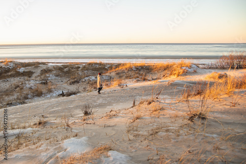 Woman walking on the Ssand dunes with pine forest over sea in the winter at White sea, Arkhangelsk