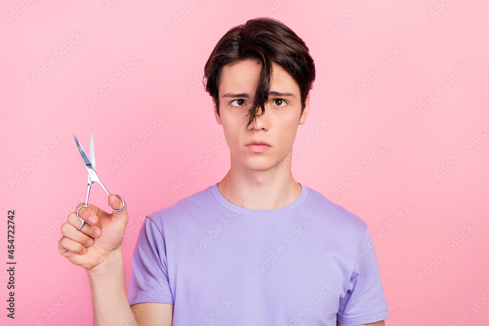 Portrait of attractive worried sullen guy cutting hair curl solution isolated over pink pastel color background Portrait of attractive worried sullen guy cutting hair curl solution isolated over pink pastel color background