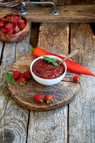 raspberry sauce with chili. Wooden background, side view.