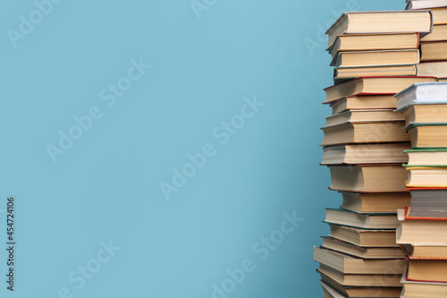Many hardcover books on turquoise background, space for text. Library material