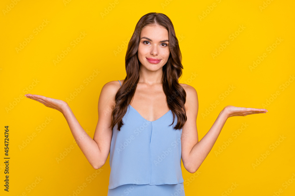 Photo of young attractive woman happy positive smile hold hand product promo alternative isolated over yellow color background Photo of young attractive woman happy positive smile hold hand product promo alternative isolated over yellow color background