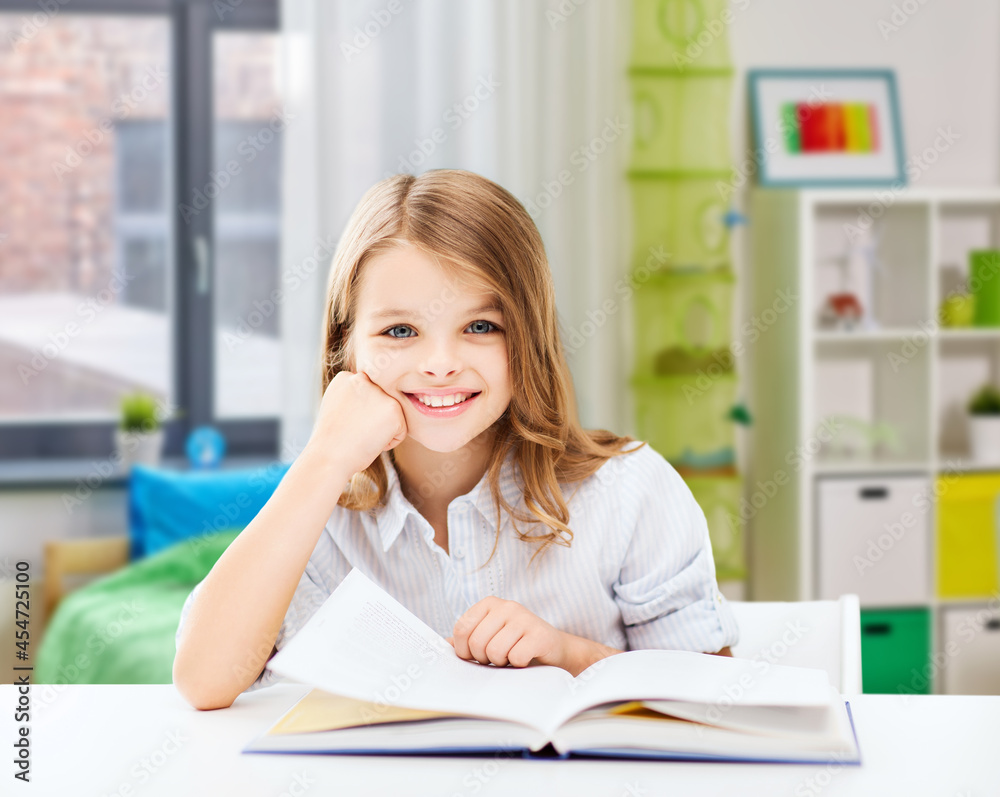 education and school concept - happy smiling student girl reading book over home background education and school concept - happy smiling student girl reading book over home background