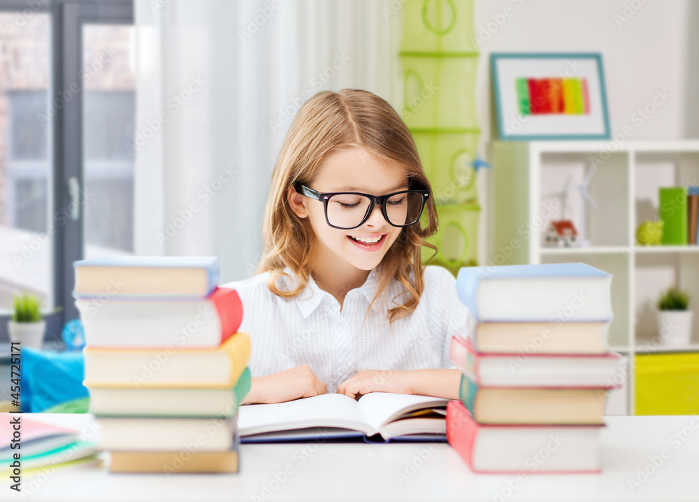 education and school concept - happy smiling student girl in glasses reading book over home background education and school concept - happy smiling student girl in glasses reading book over home background