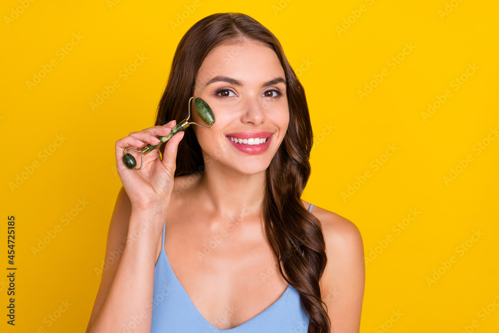 Photo of young cheerful woman happy positive smile make face massage lifting isolated over yellow color background Photo of young cheerful woman happy positive smile make face massage lifting isolated over yellow color background