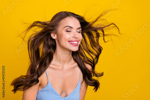 Profile side photo of young attractive woman happy positive smile wind blow haircare conditioner isolated over yellow color background