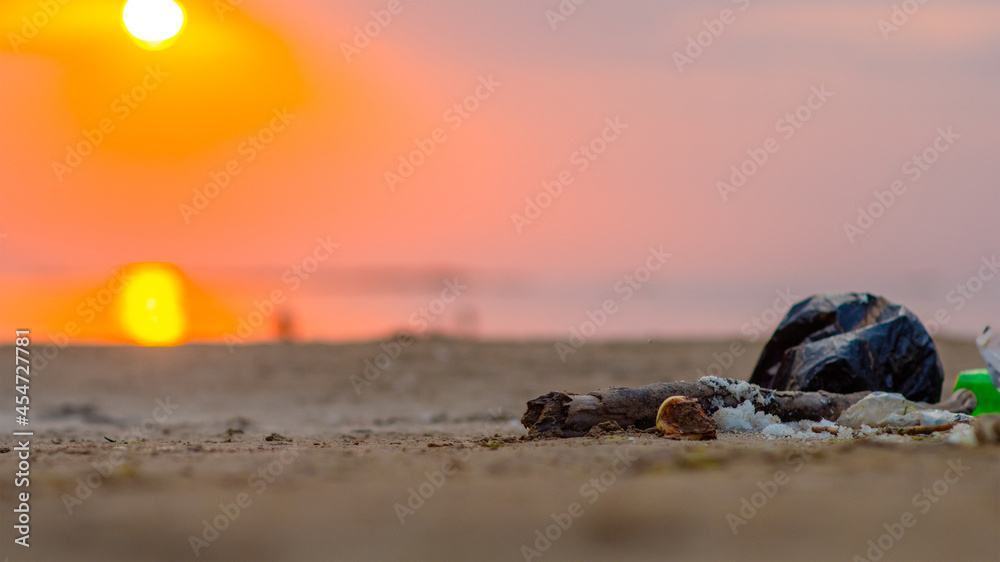 garbage lying on a beach of a sea at sunset. Environmental pollution. Ecological problem. Empty space for text