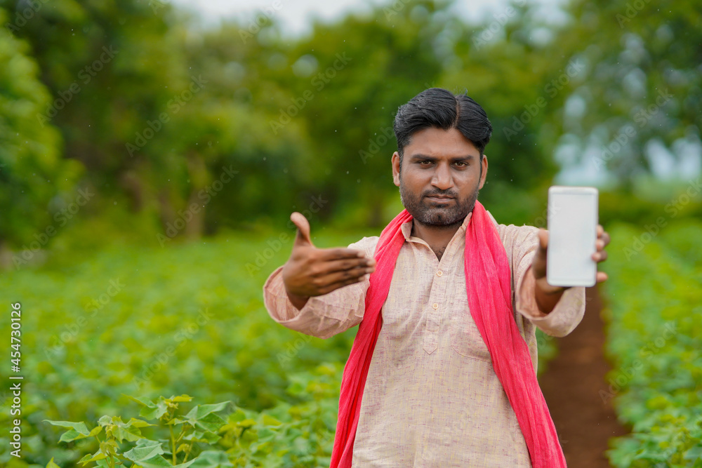 Fototapeta premium Young indian farmer showing smartphone at agriculture field.