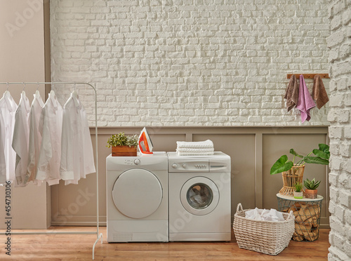 Modern laundry room with washing machine, plant and brick wall concept. © UnitedPhotoStudio