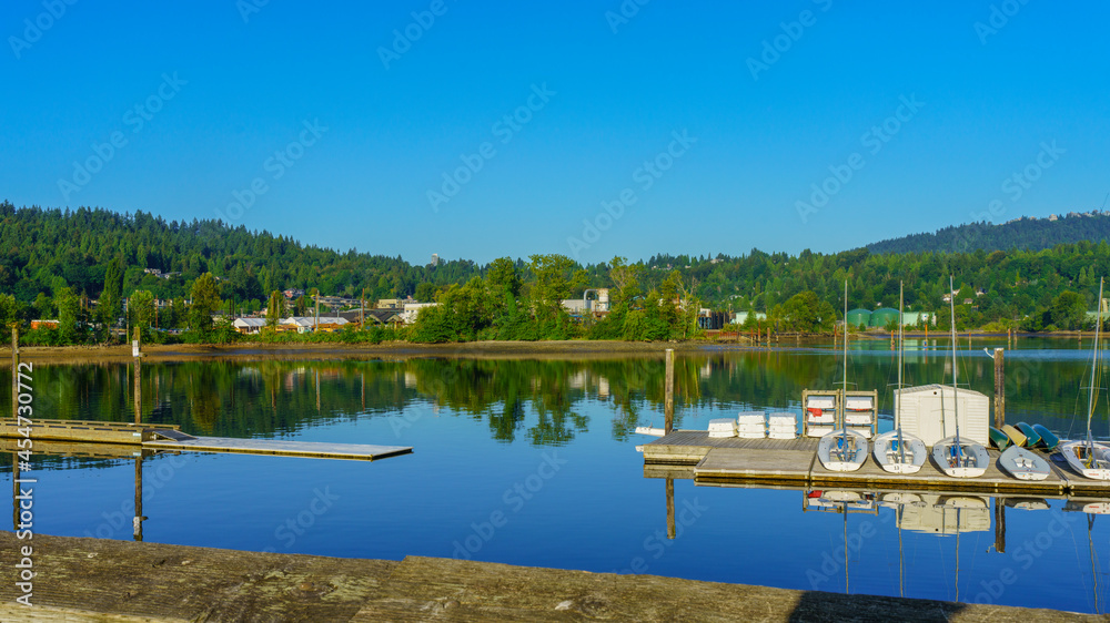 Sailboats reflected in tranquil waters of Burrard Inlet, BC, overlooking industrial plant and oil storage tanks right on the water's edge Sailboats reflected in tranquil waters of Burrard Inlet, BC, overlooking industrial plant and oil storage tanks right on the water's edge