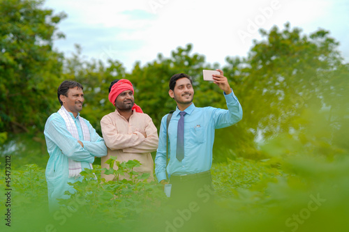 Photography Young indian agronomist or banker taking selfie with farmer at agriculture field