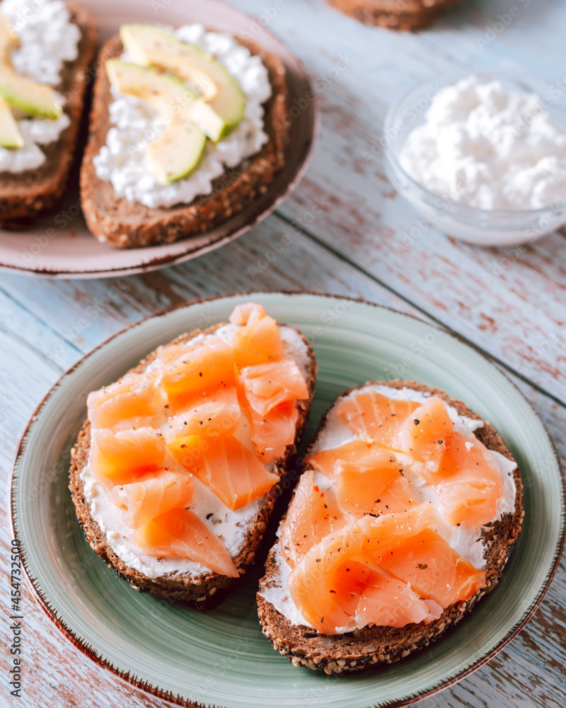 Healthy toasts with smoked salmon and avocado on plates for breakfast