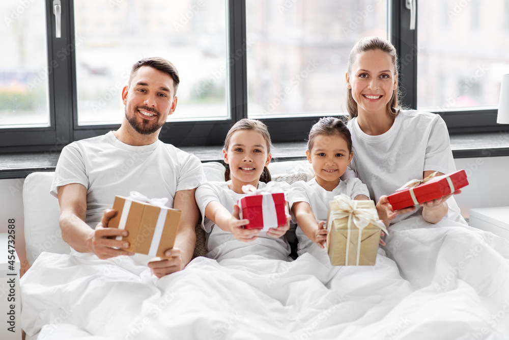 family, winter holidays and people concept - happy mother, father and two daughters in pajamas with christmas gifts in bed at home family, winter holidays and people concept - happy mother, father and two daughters in pajamas with christmas gifts in bed at home