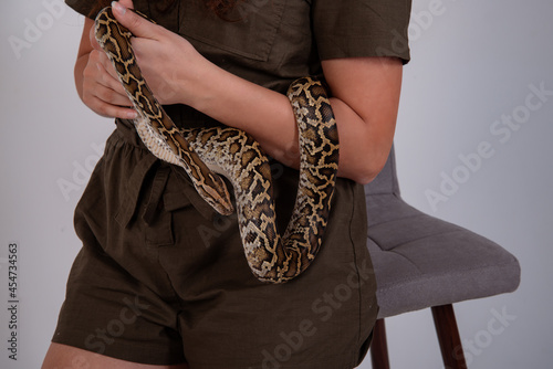Young beautiful woman with a snake on her body. The girl stands on a white background. Isolate. Exotic reptiles.