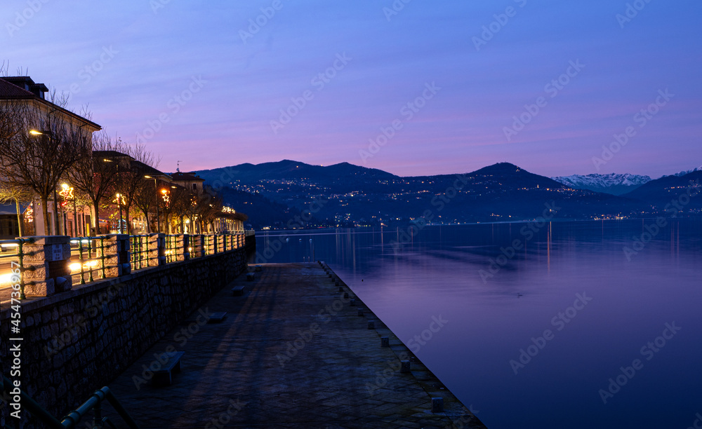 touching landscape of Lake Maggiore with illuminated lakefront in Arona, Piedmont, Italy.