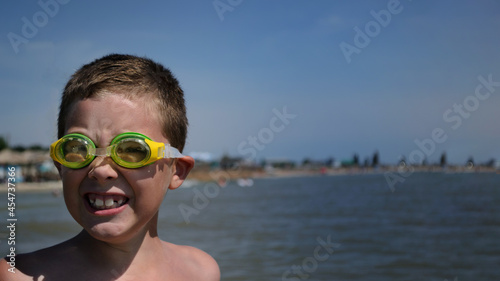 joyful boy with diving goggles in the water. happy childhood concept,
