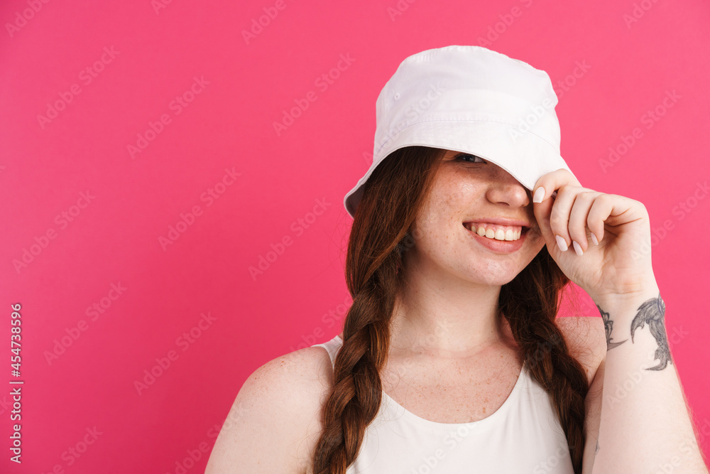 Young ginger woman with pigtails smiling and holding her panama Young ginger woman with pigtails smiling and holding her panama