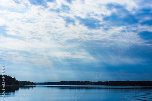 The rays of God in the river landscape. The sun's rays shine through the clouds over the water surface and the shore. Copy space