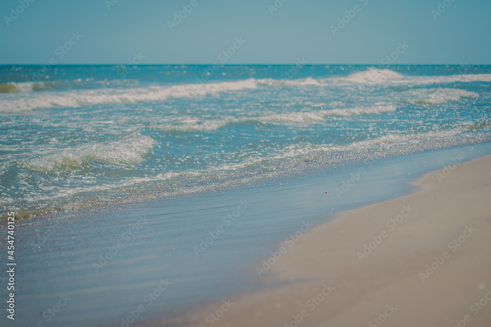 beautiful sea at noon in summer, clear water, sand beach. silent waves are illuminated by the midday sun. seascape under the midday.