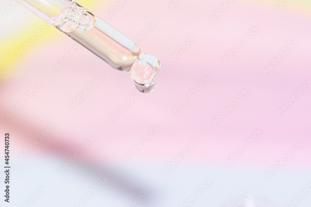 detail of pipette dropper with a drop of hydrating face serum on a pink and blue unicorn background detail of pipette dropper with a drop of hydrating face serum on a pink and blue unicorn background
