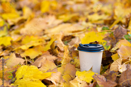 Close-up of a craft cup of hot coffee in fallen yellow leaves