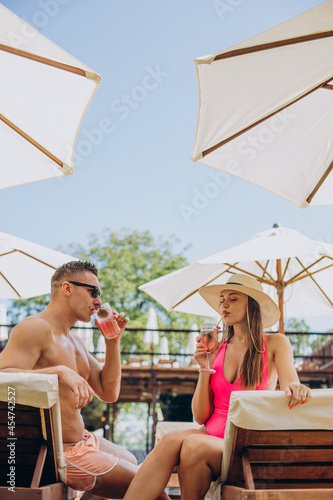 Man and woman drinking coctails by the pool © Petro