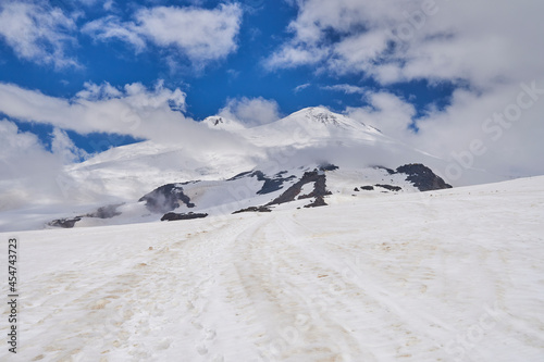 snow-capped peaks bright sun and white clouds over the peaks of the Caucasus mountains